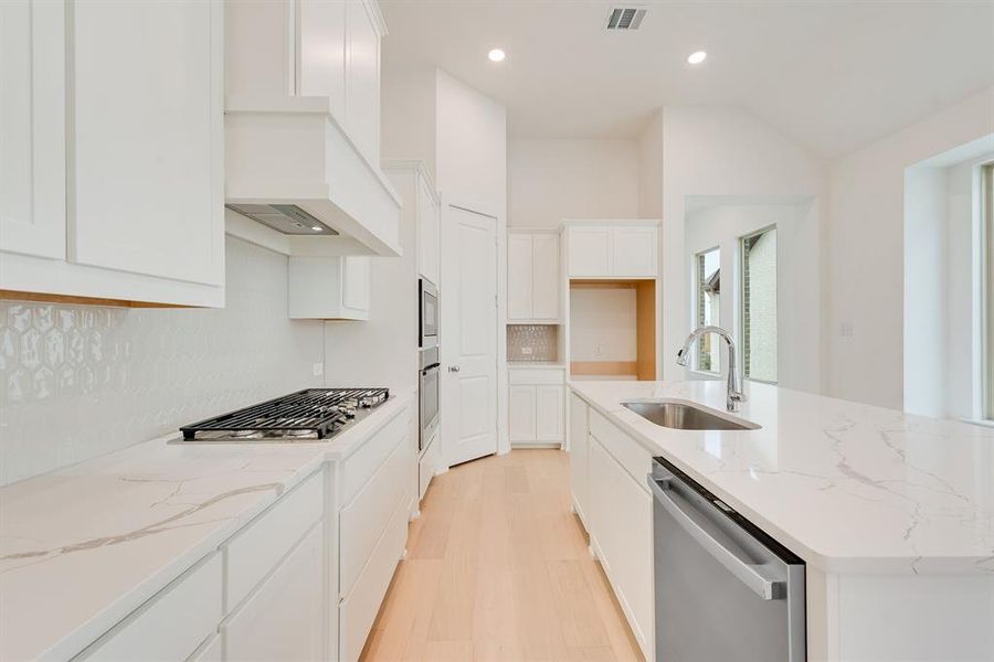 Kitchen with light stone countertops, stainless steel appliances, light wood-style flooring, recessed lighting, and white cabinets Kitchen with light stone countertops, stainless steel appliances, light wood-style flooring, recessed lighting, and white cabinets