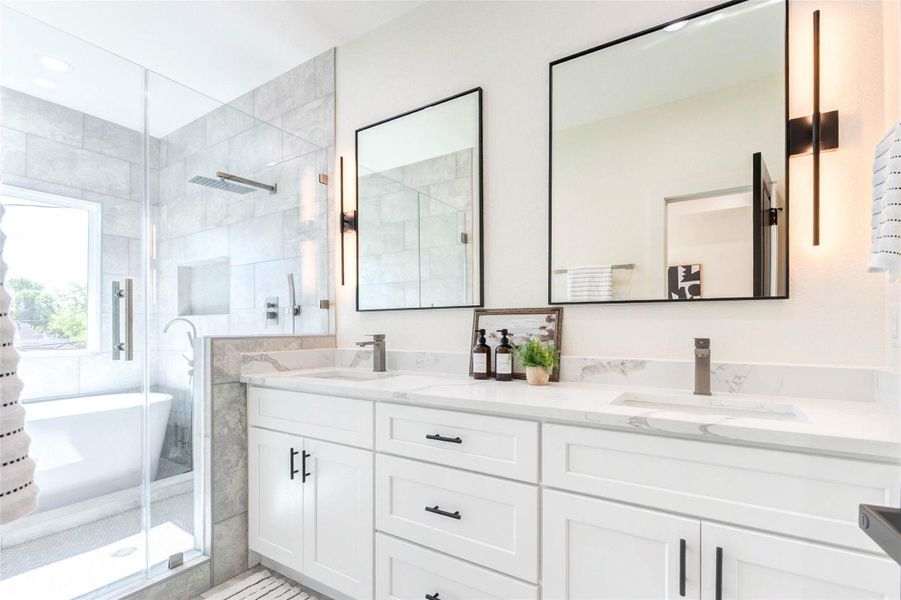 The dual-sink vanity is topped with marble-style quartz and accented by minimalist black hardware and vertical sconce lighting.