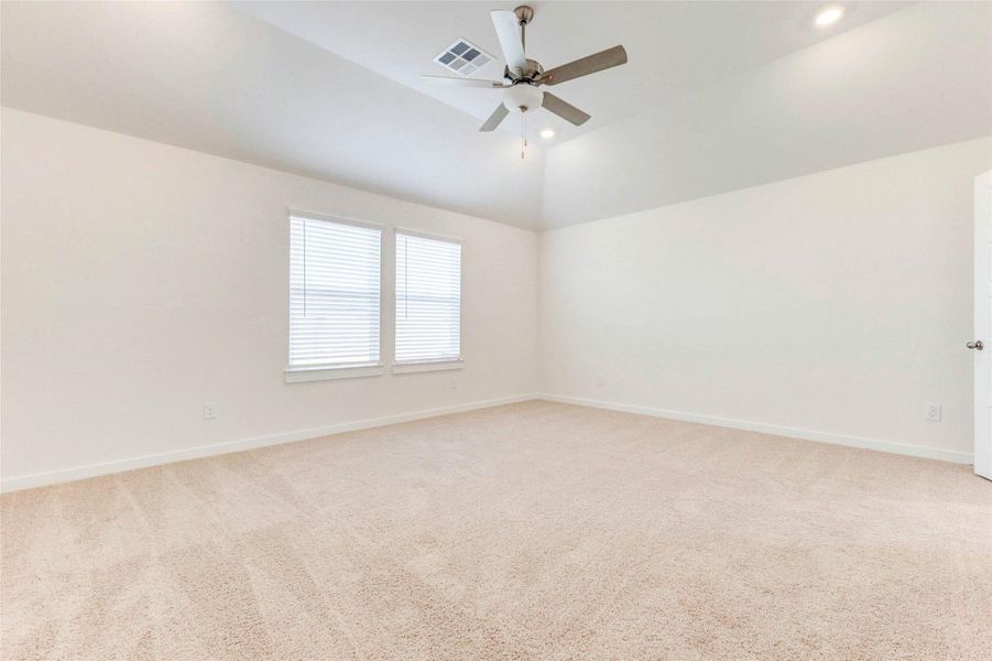 The spacious primary suite features a vaulted ceiling with recessed lighting and a ceiling fan, creating a serene and airy retreat. Plush carpet adds warmth underfoot, while large windows bathe the space in natural light, perfect for slow mornings or restful evenings. The spacious primary suite features a vaulted ceiling with recessed lighting and a ceiling fan, creating a serene and airy retreat. Plush carpet adds warmth underfoot, while large windows bathe the space in natural light, perfect for slow mornings or restful evenings.