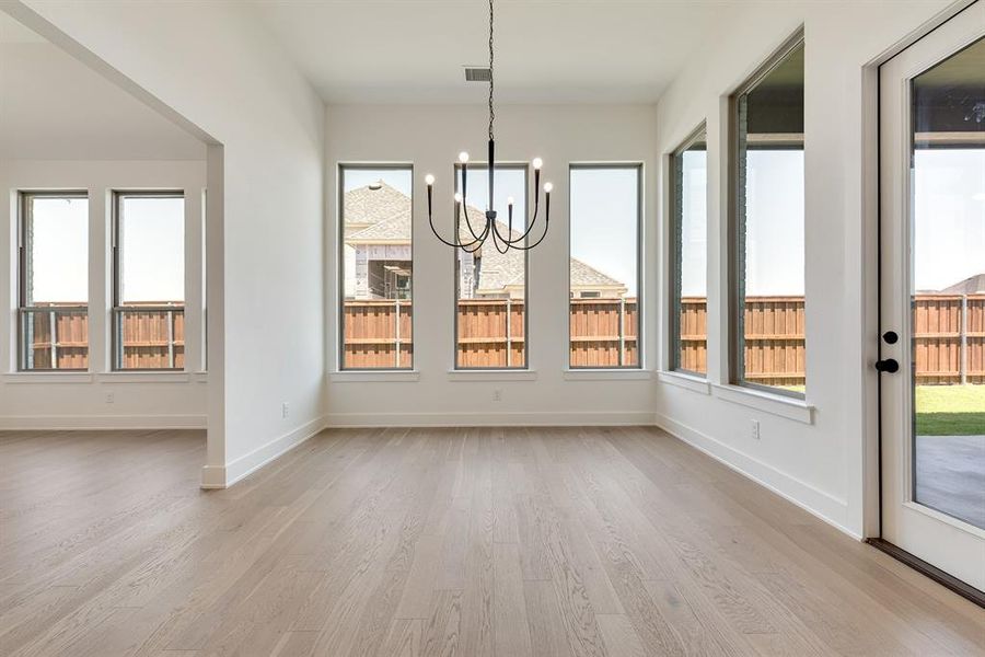 Unfurnished dining area with light wood-type flooring, a chandelier, and plenty of natural light Unfurnished dining area with light wood-type flooring, a chandelier, and plenty of natural light