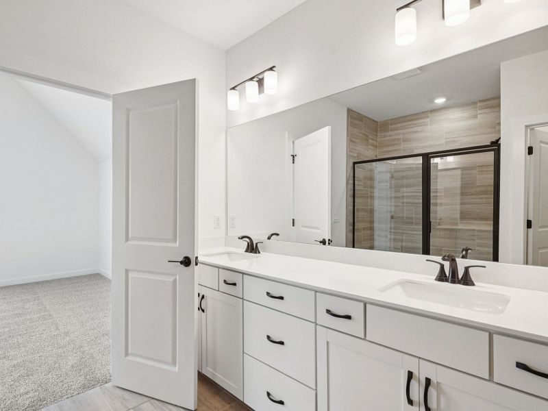 The primary bathroom offers dual vanity sinks and a walk-in shower.
