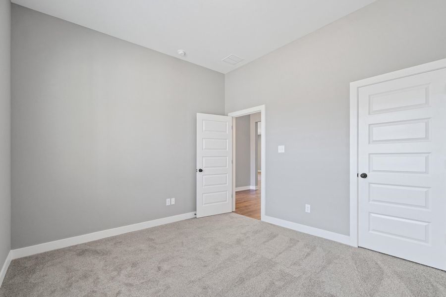 Unfurnished bedroom with light carpet and baseboards