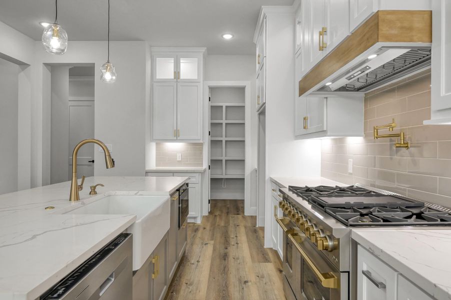 The kitchen features a farm style sink, warm toned hardware, stainless steel appliances and a sleek tile backsplash. The kitchen features a farm style sink, warm toned hardware, stainless steel appliances and a sleek tile backsplash.