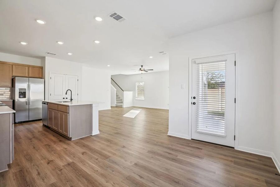 An open concept living area showcases beautiful flooring, a modern kitchen island, and a clear view to the stairs. An open concept living area showcases beautiful flooring, a modern kitchen island, and a clear view to the stairs.