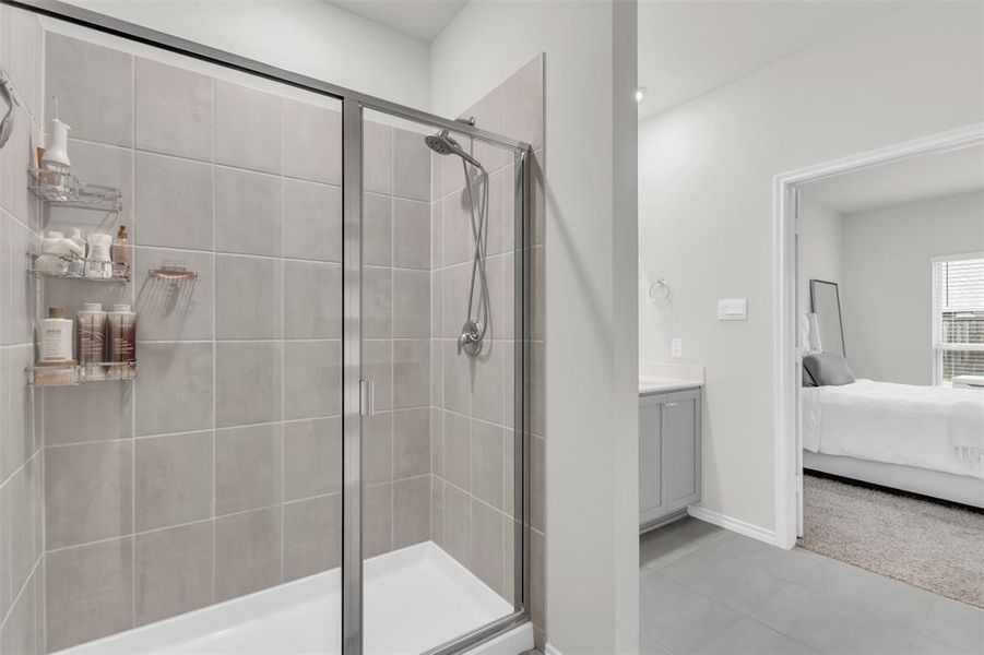 Ensuite bathroom with a stall shower, vanity, tile patterned floors, and baseboards Ensuite bathroom with a stall shower, vanity, tile patterned floors, and baseboards