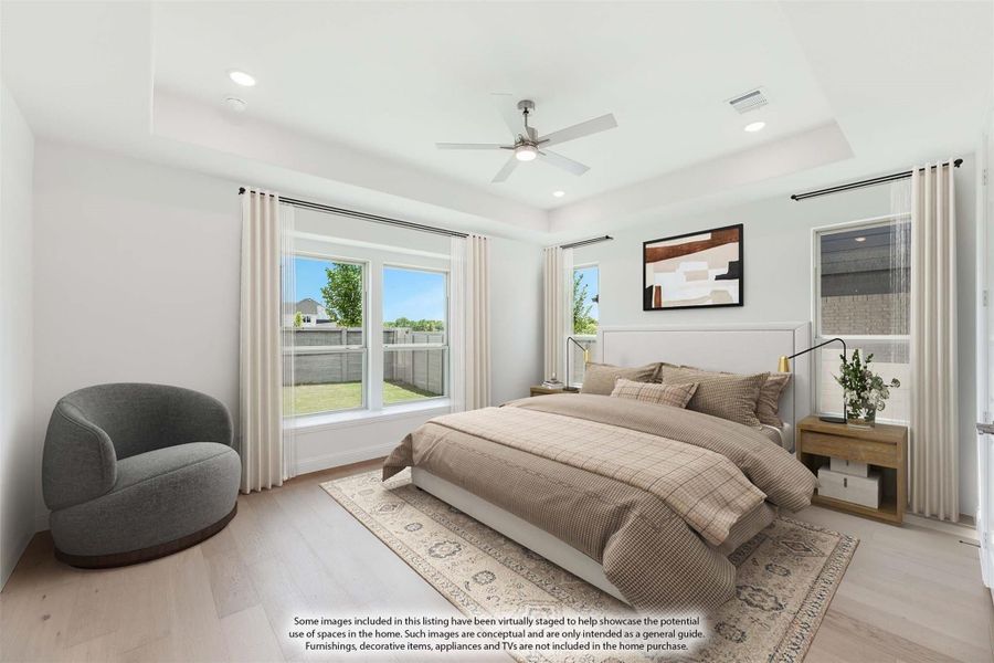 Bedroom with tray ceiling, ceiling fan, hardwood floors, and large windows with backyard view
