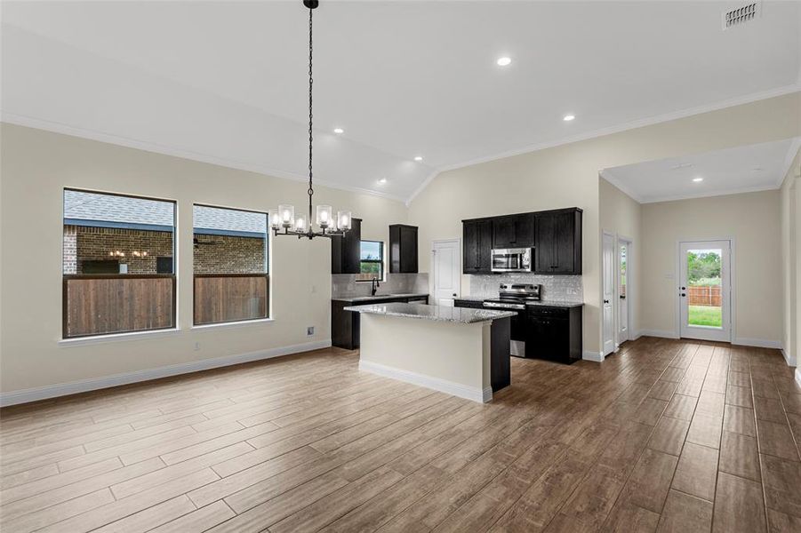 Open-concept living space featuring wood-finish flooring, vaulted ceilings, and recessed lighting