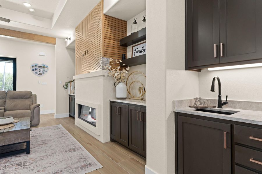 Living room with a glass covered fireplace, light wood finished floors, baseboards, and wet bar Living room with a glass covered fireplace, light wood finished floors, baseboards, and wet bar
