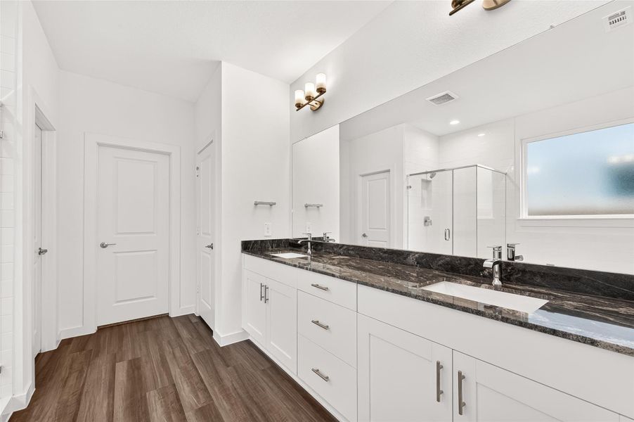 Primary Ensuite: The spa-like ensuite features double vanities with quartz countertops, a soaking tub, a separate glass-enclosed shower, a linen closet, and a massive walk-in closet with ample shelving and hanging space.