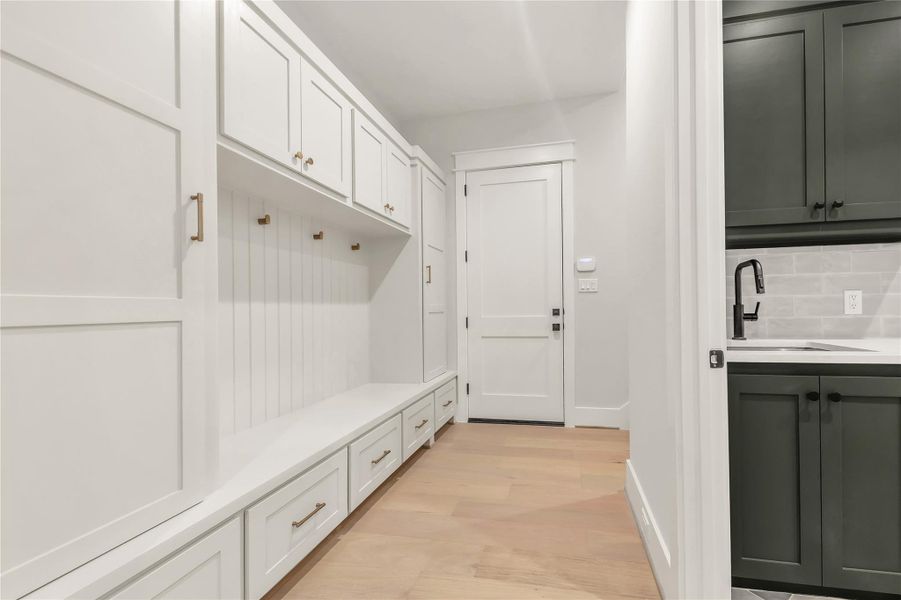 Mudroom with light wood finished floors and a sink