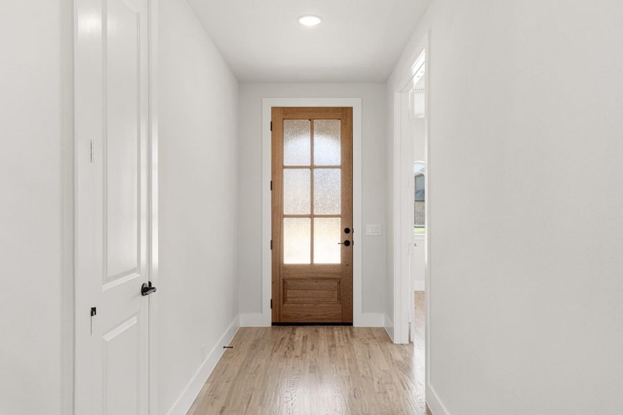Narrow entryway with wood front door featuring glass panels and light hardwood floors