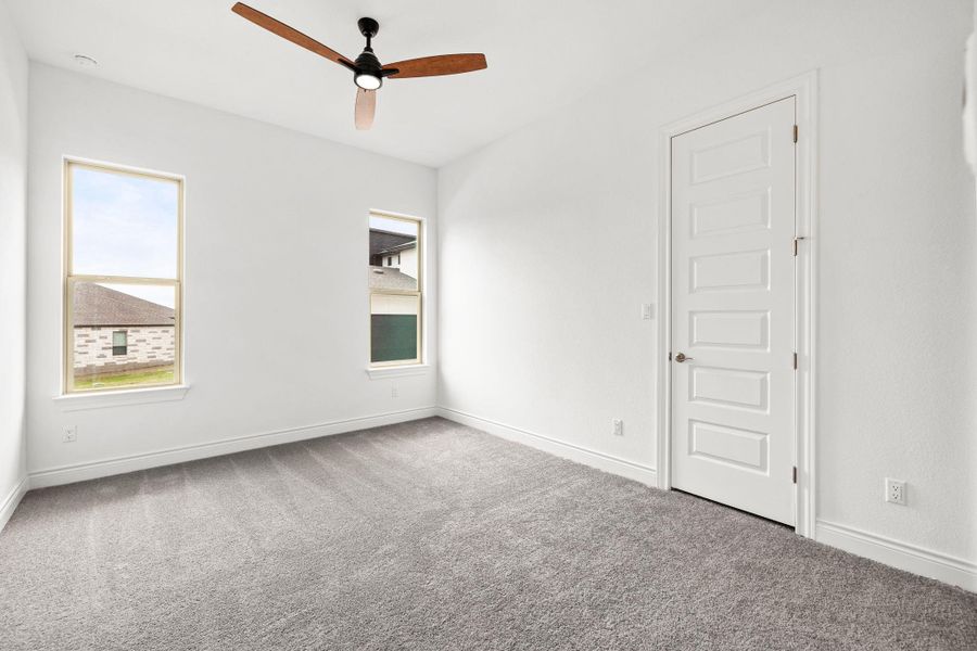 Carpeted empty room featuring ceiling fan and baseboards