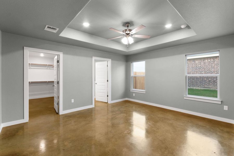 Recessed lighting illuminates the tray ceiling, highlighting the polished concrete floors in this spacious room.