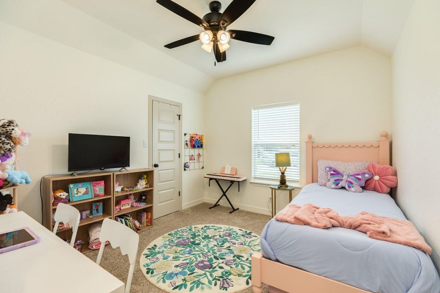 This photo shows a cozy size bedroom, The room has a ceiling fan, a window providing natural light, creating a cheerful atmosphere.