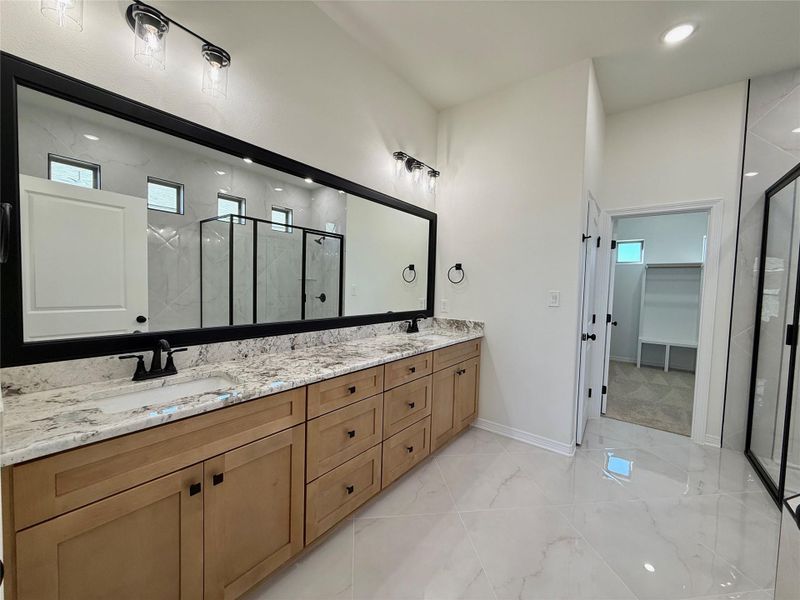 Bathroom with a marble finish shower, double vanity, a spacious closet, recessed lighting, and light marble finish floors