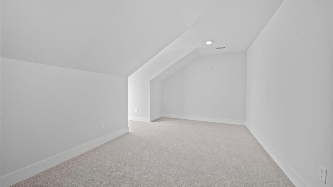 Refined bonus room with comfortable carpeted flooring and tasteful design throughout