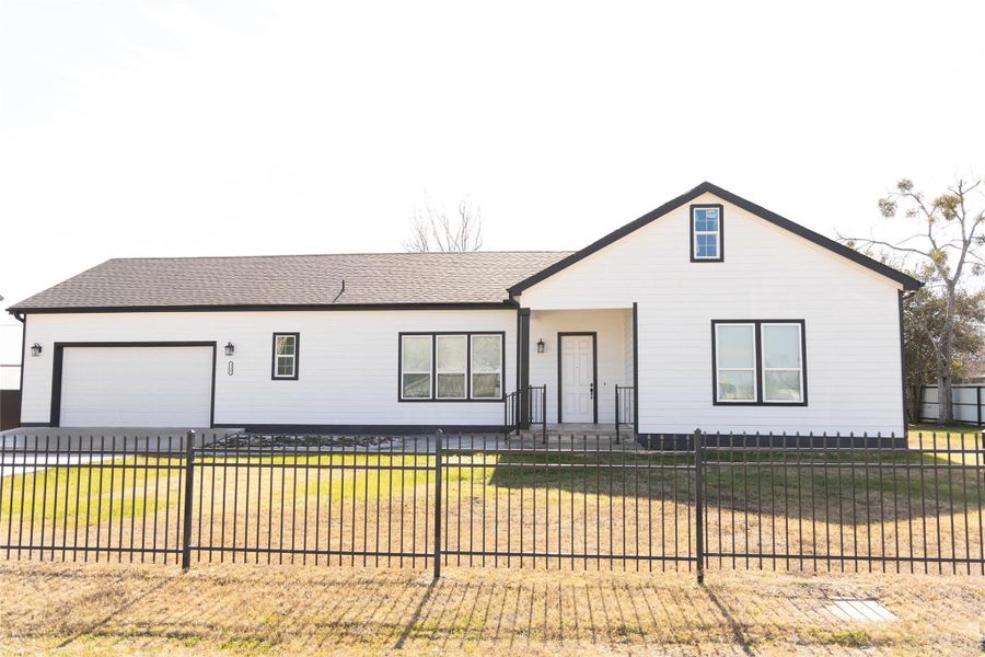 View of front of home with roof with shingles, a fenced front yard, a porch, an attached garage, and driveway