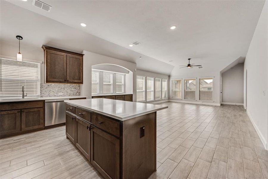 Kitchen featuring light countertops, decorative backsplash, ceiling fan, decorative light fixtures, and open floor plan Kitchen featuring light countertops, decorative backsplash, ceiling fan, decorative light fixtures, and open floor plan