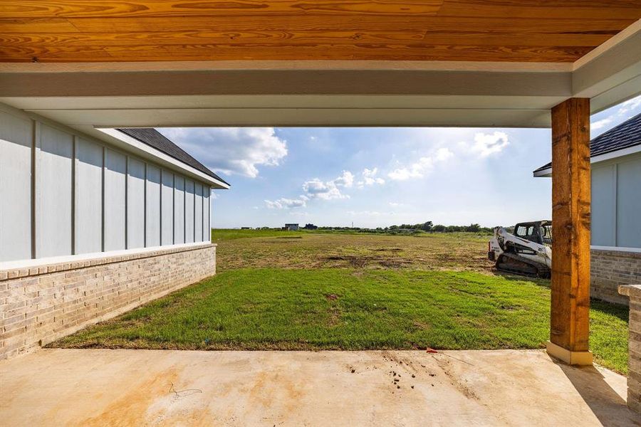 View of green lawn featuring a patio area View of green lawn featuring a patio area