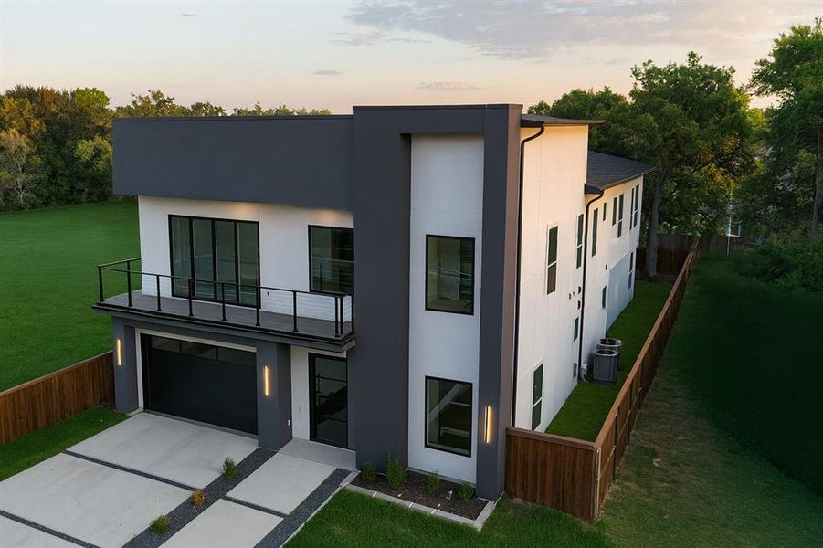 Contemporary house featuring stucco siding, concrete driveway, a balcony, and a garage