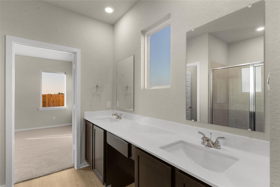 Bathroom with double vanity, a shower stall, and light wood-type flooring