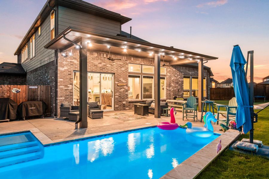 Step outside to a stunning backyard retreat featuring a sparkling pool and expansive covered patio. With recessed lighting, dual ceiling fans, and ample space for outdoor entertaining, this area is perfect for both relaxing evenings and lively gatherings. The sleek brick exterior and large windows seamlessly connect the indoor and outdoor living spaces, creating a true extension of the home.