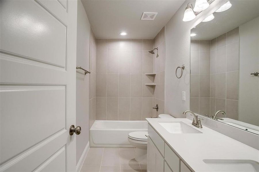Bathroom featuring light tile patterned flooring, double vanity, shower / bath combination, and recessed lighting Bathroom featuring light tile patterned flooring, double vanity, shower / bath combination, and recessed lighting