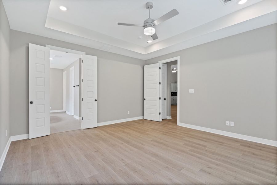 Spacious room featuring light wood-finish flooring, light gray wall paint, and white trim Spacious room featuring light wood-finish flooring, light gray wall paint, and white trim