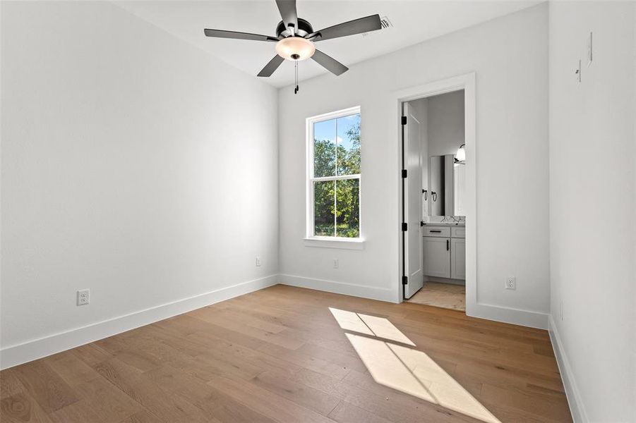 Unfurnished bedroom with light wood-style floors, ceiling fan, and ensuite bathroom Unfurnished bedroom with light wood-style floors, ceiling fan, and ensuite bathroom