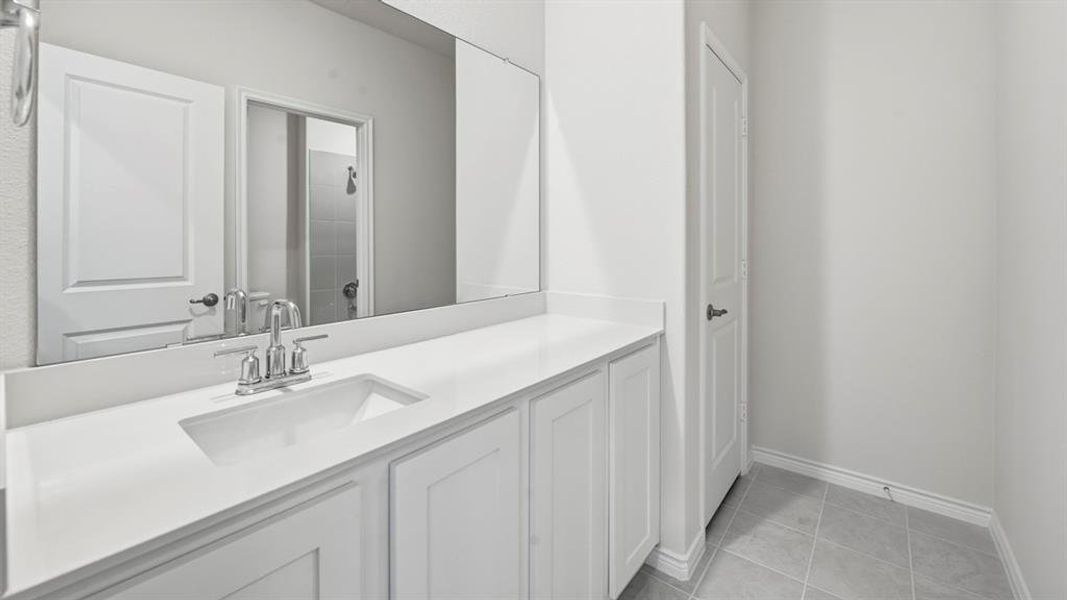 Bathroom featuring a tile shower, vanity, and light tile patterned floors Bathroom featuring a tile shower, vanity, and light tile patterned floors