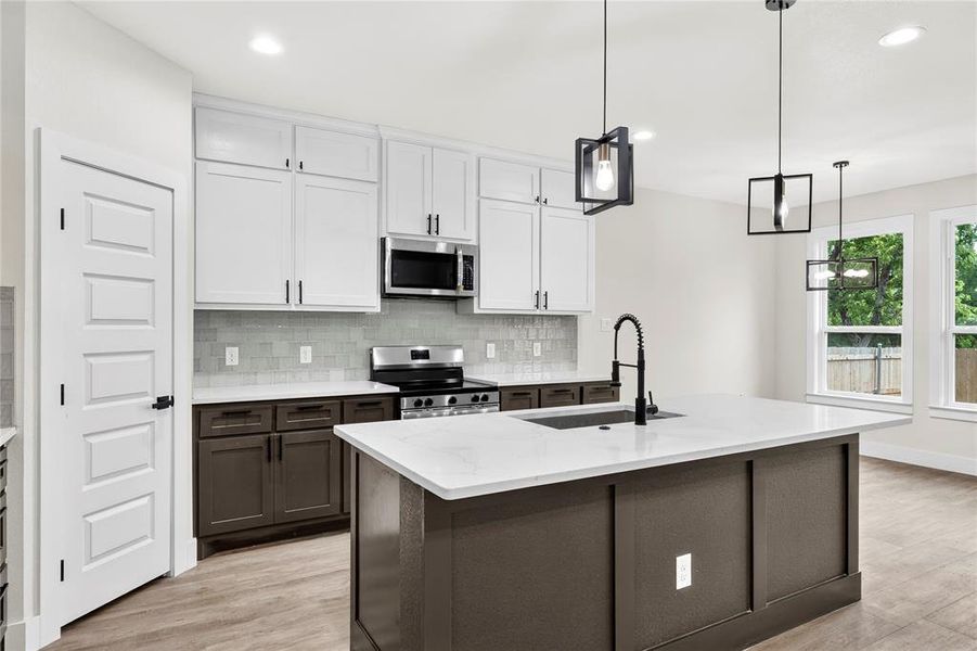 Open-concept room featuring wood-finish flooring, multiple windows, a rear exterior door with a grid pattern, a modern geometric chandelier, and white baseboards