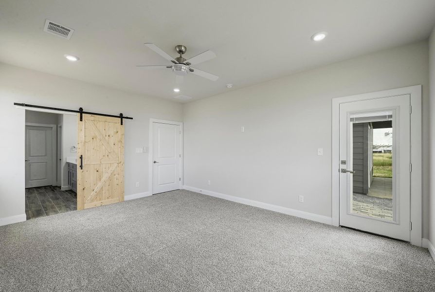 Unfurnished bedroom with carpet, a barn door, recessed lighting, connected bathroom, and ceiling fan