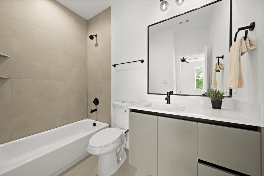 This secondary bathroom on the third floor features modern fixtures, a sleek vanity, and a shower-tub combo.