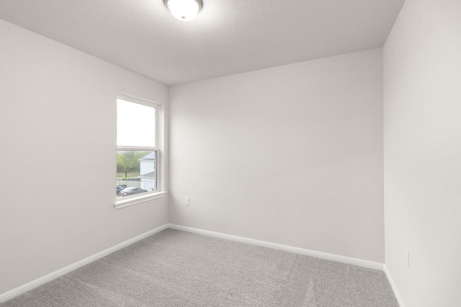 This room features neutral-toned walls, a window providing natural light, and plush carpet flooring
