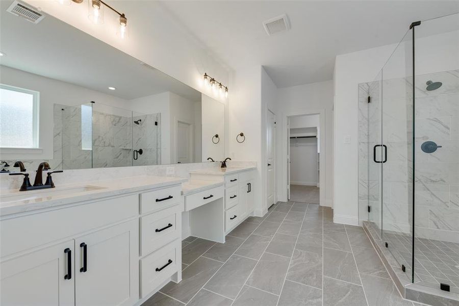 Bathroom featuring a shower with shower door, tile patterned floors, and double sink vanity