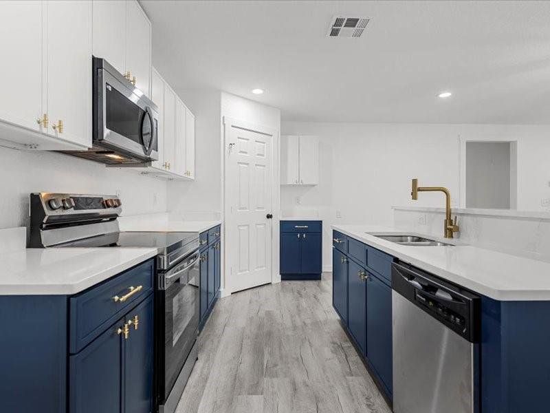 Kitchen featuring blue cabinets, stainless steel appliances, white cabinetry, light wood-type flooring, and recessed lighting