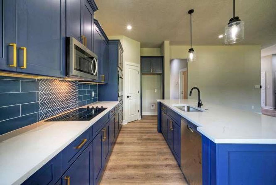 Bold blue cabinetry and pristine countertops define this newly designed kitchen with modern fixtures.