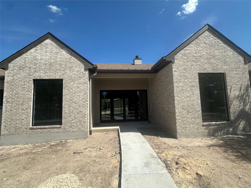 Symmetrical brick gables flank a recessed entrance under a clear blue sky.