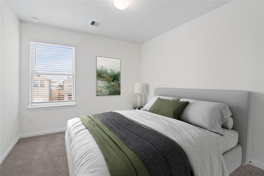 Secondary bedroom features plush carpet, custom paint, lighting, ample closet space, and a large window with privacy blinds.