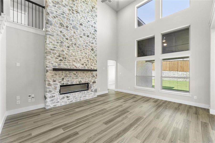 Double-height living space featuring a floor-to-ceiling stone fireplace with a modern linear insert and wood mantel Double-height living space featuring a floor-to-ceiling stone fireplace with a modern linear insert and wood mantel