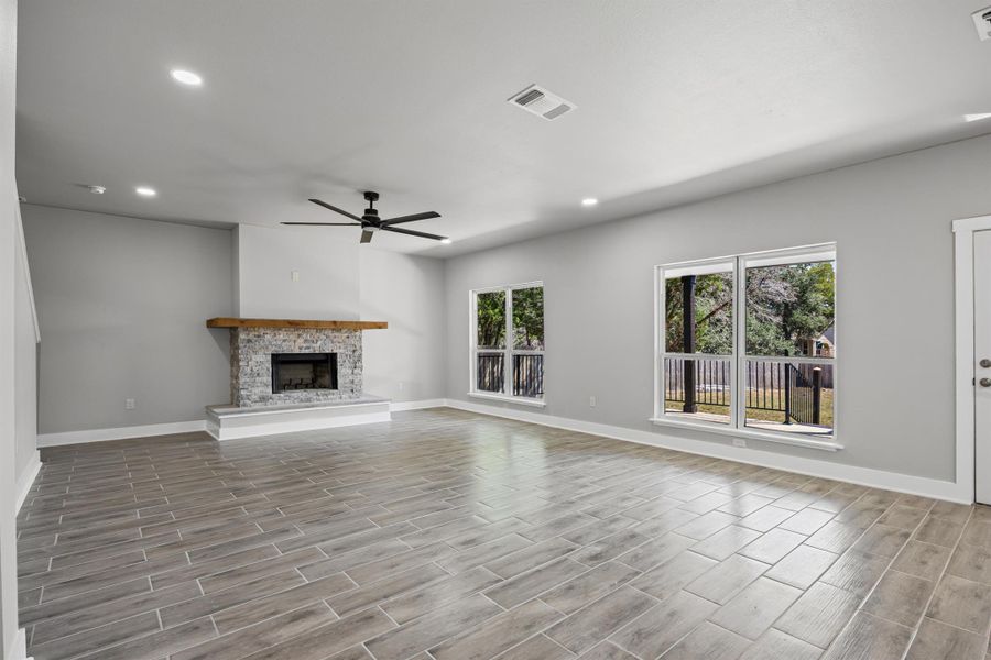 Unfurnished living room featuring recessed lighting, wood tiled floors, a fireplace with raised hearth, and ceiling fan Unfurnished living room featuring recessed lighting, wood tiled floors, a fireplace with raised hearth, and ceiling fan