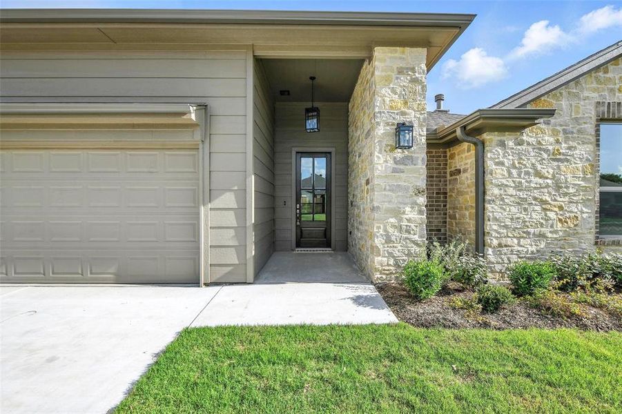 View of exterior entry with stone siding and driveway