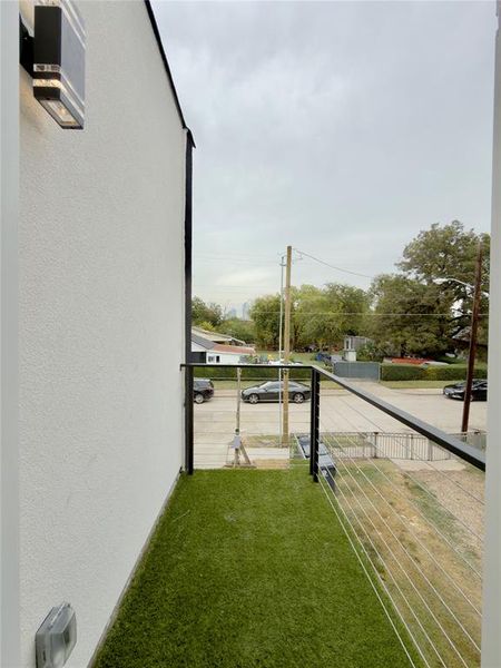 View of grassy yard featuring a balcony