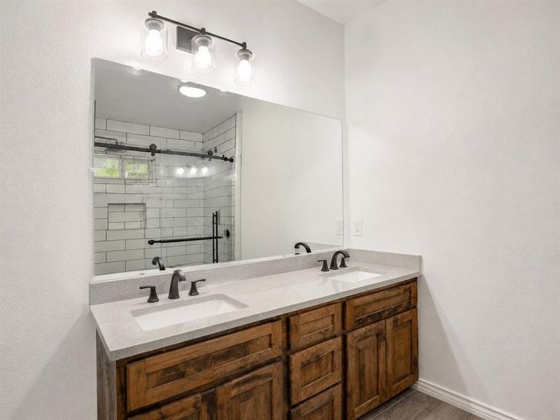Dual vanity with stone countertop and dark wood-finish cabinetry