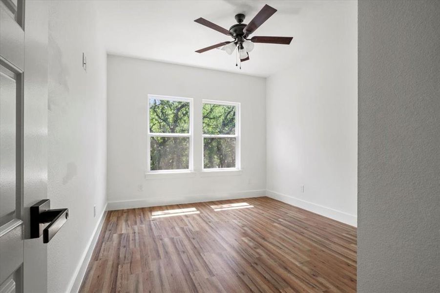 Empty room with wood finished floors, a ceiling fan, and a textured wall