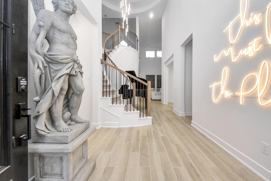 WELCOME HOME! Spacious foyer with curved staircase with wood-look flooring and soaring ceilings.