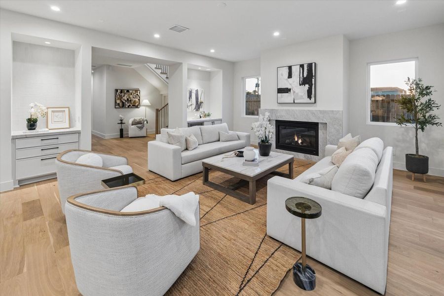 The spacious living room offers 10-foot ceilings, pre-wired for surround sound, a 42-inch gas fireplace with a polished Carrara marble mantel and surround, a dry bar with Carrara marble countertop featuring Koto System LED sunset lights, and seamless access to the backyard.