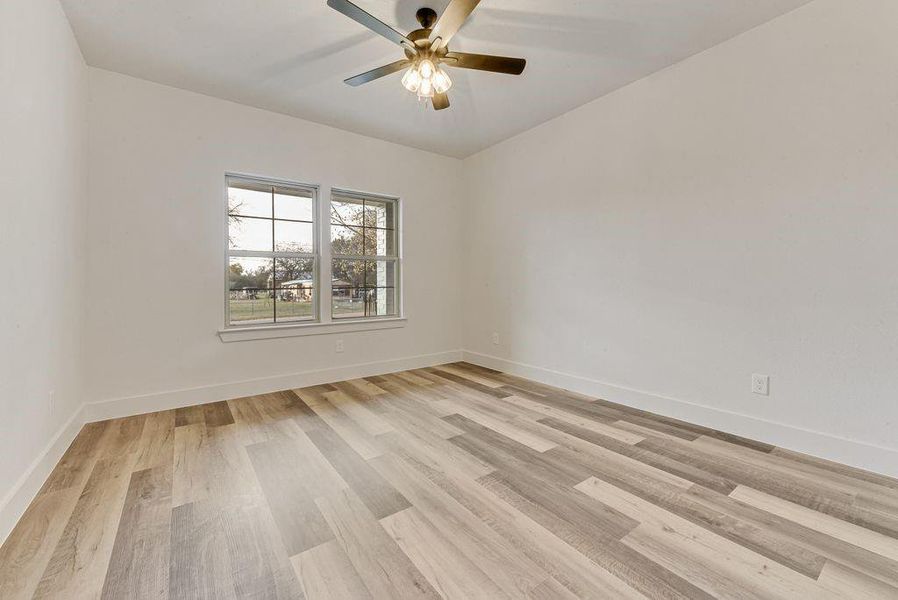 Empty room featuring light wood finished floors and a ceiling fan Empty room featuring light wood finished floors and a ceiling fan