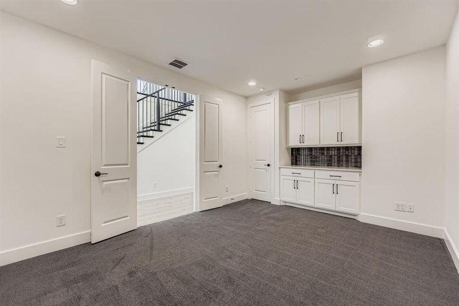 Unfurnished room featuring dark carpet, recessed lighting, and stairs