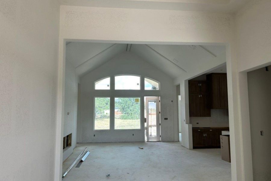 Unfurnished living room with high vaulted ceiling and a fireplace with raised hearth Unfurnished living room with high vaulted ceiling and a fireplace with raised hearth
